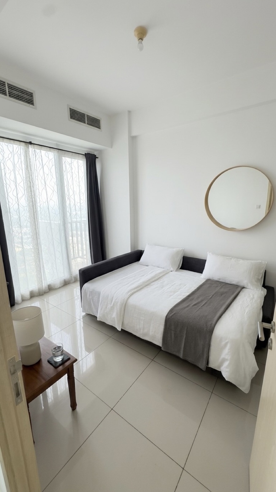 Bedroom with daybed, round mirror and sheer curtains