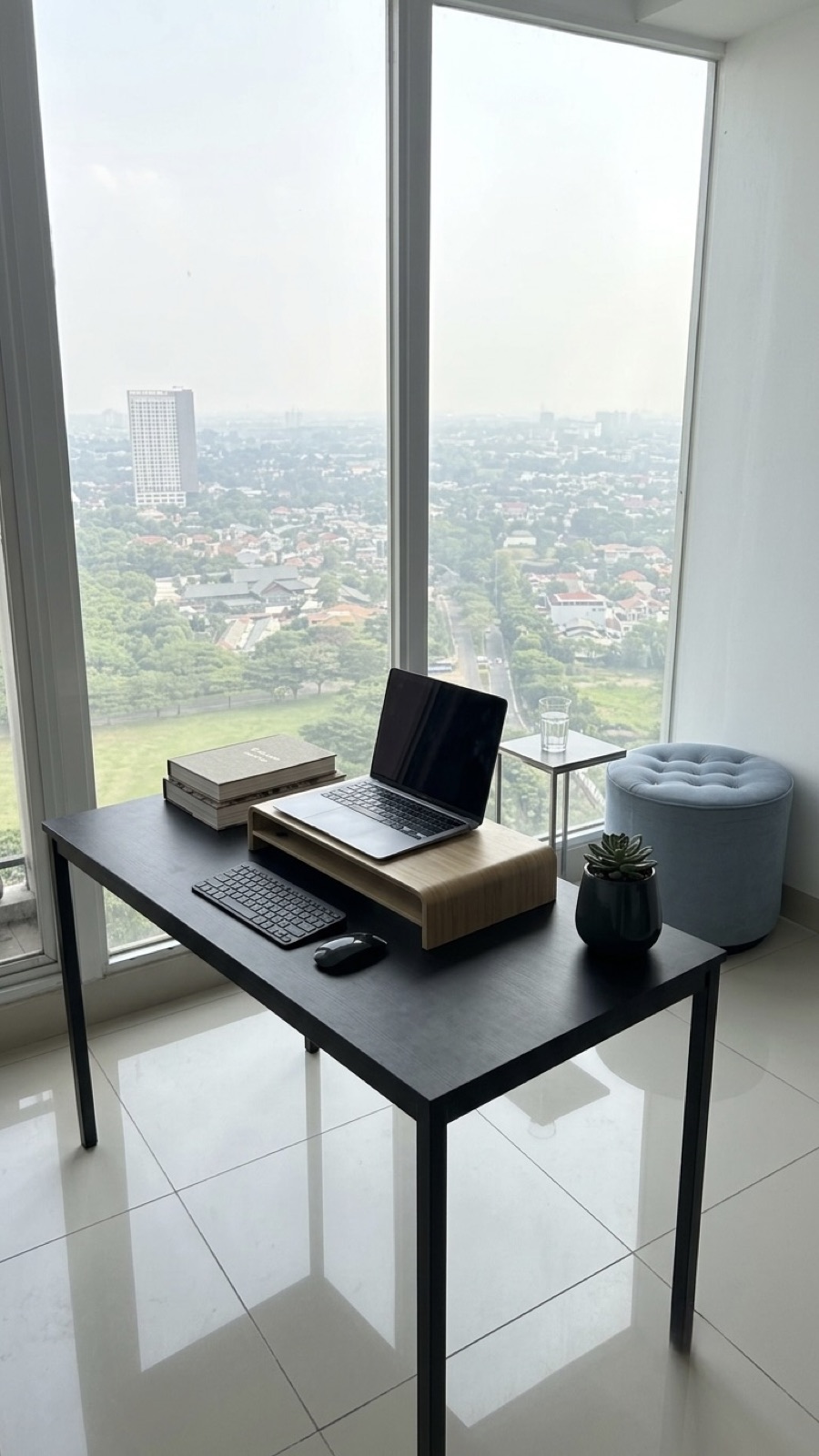 Work desk with laptop facing floor-to-ceiling windows over the park