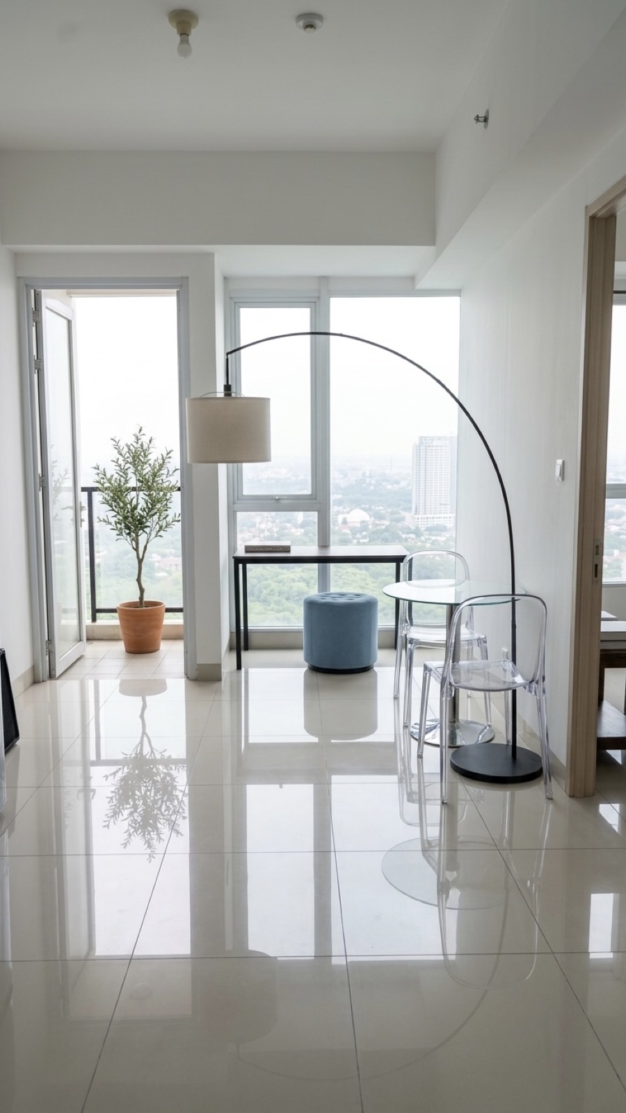 Living area with arc floor lamp, glass dining table and balcony access