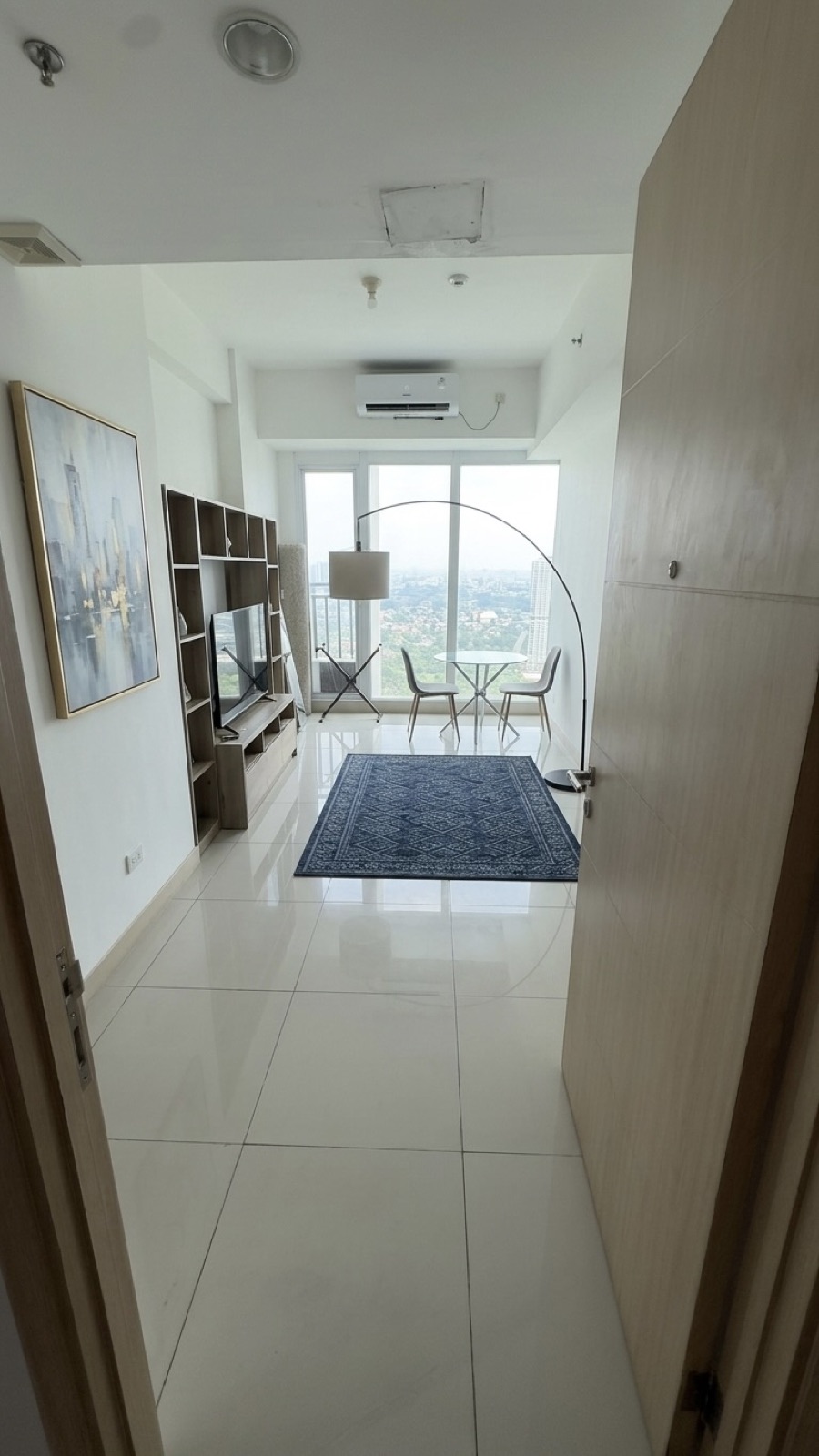 Living room with TV shelving, rug and dining nook by the window